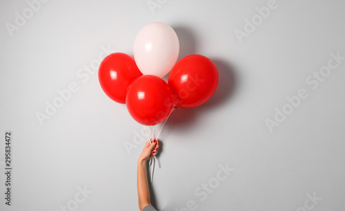 woman hold red and white air ballons in hand with copy space for your text indoor .stylish birthday party or holidays with balloons.four red balloons on the gray background with copy space for text.