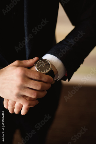 Male businessman dresses and adjusts his watch, preparing for a meeting. Clock