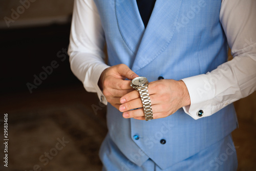 Male businessman dresses and adjusts his watch, preparing for a meeting. Clock