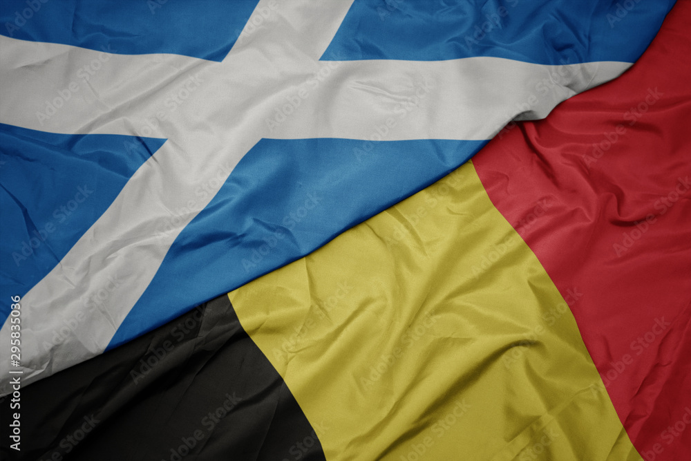 waving colorful flag of belgium and national flag of scotland.