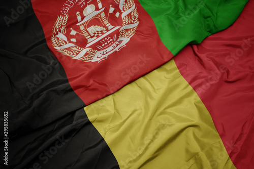 waving colorful flag of belgium and national flag of afghanistan.