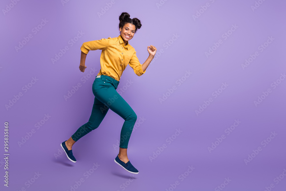 Full length profile photo of pretty dark skin lady jumping high speed rushing to finish line wear casual yellow shirt trousers isolated purple color background