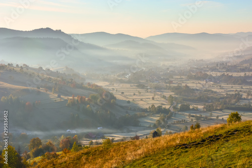 Beautiful landscape mountain hill meadow sunrise foggy morning village Bucovina Romania 