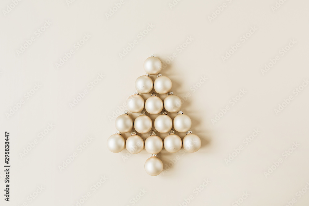 Christmas / New Year composition. Christmas tree symbol made of gold Christmas baubles on beige background. Flat lay, top view festive holiday concept. Christmas / New Year composition. Christmas tree symbol made of gold Christmas baubles on beige background. Flat lay, top view festive holiday concept.