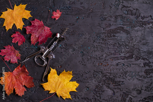 Flat lay composition with wine corkscrew and autumn leaves on black background, copy space