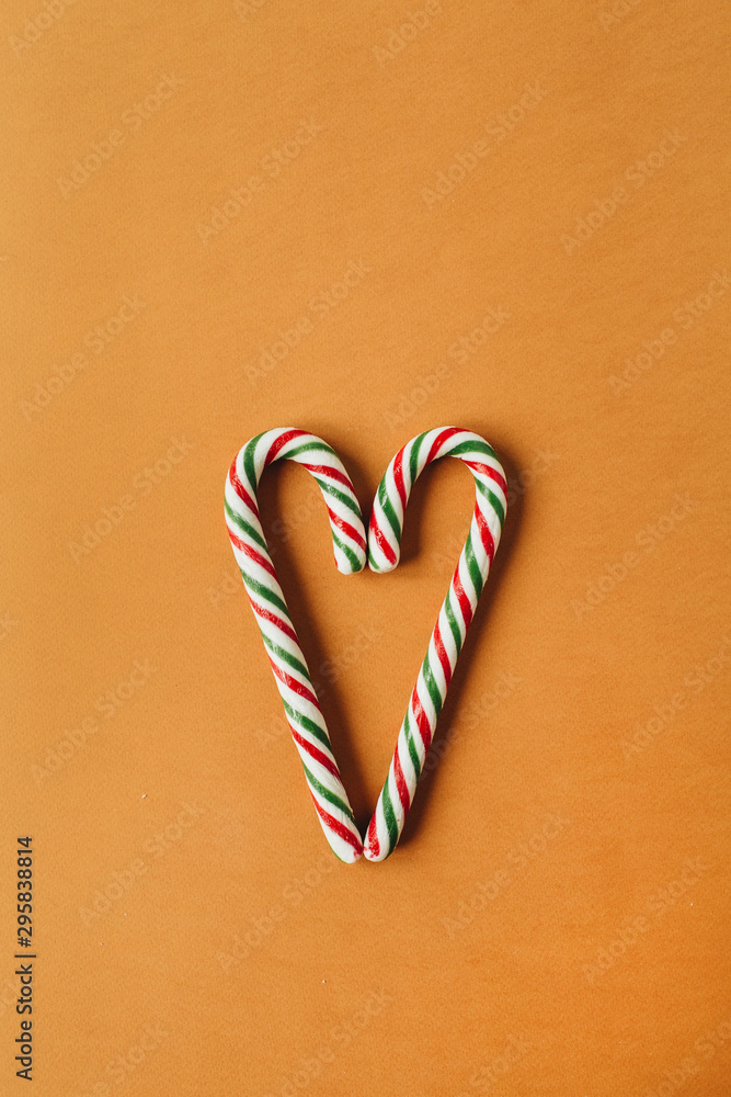 Heart symbol made of two traditional stick candies on ginger background. Flat lay, top view Christmas / New Year holiday concept. Heart symbol made of two traditional stick candies on ginger background. Flat lay, top view Christmas / New Year holiday concept.