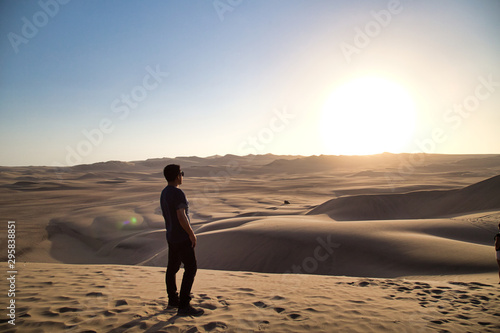 young man on sand in a desert near Huacachina  Ica region  Peru. The sunset desert viewyoung man on sand in a desert near Huacachina  Ica region  Peru. The sunset desert view