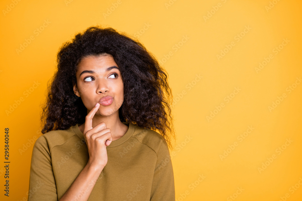 Closeup photo of pretty dark skin lady looking side empty space holding finger n chin deep thinking wear casual pullover isolated on yellow color background - obrazy, fototapety, plakaty 