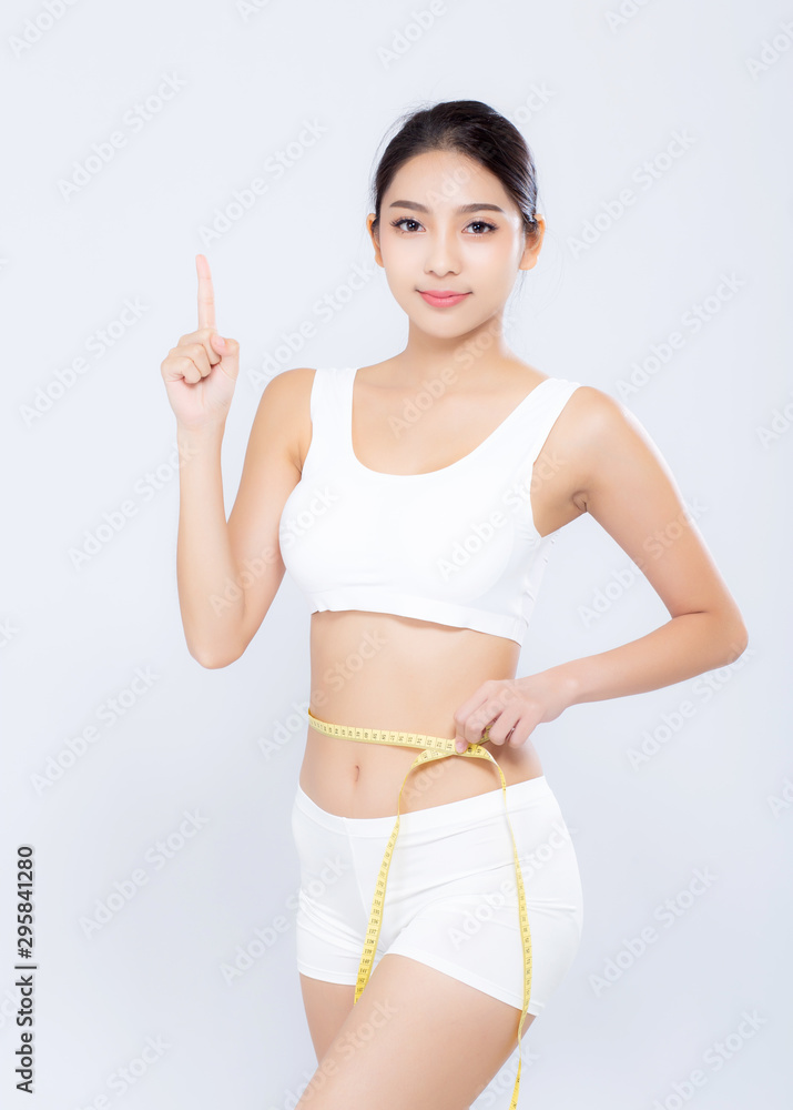 Beautiful asian woman diet and slim with measuring waist for weight finger pointing something isolated on white background, girl have cellulite loss with tape measure, health and wellness concept.