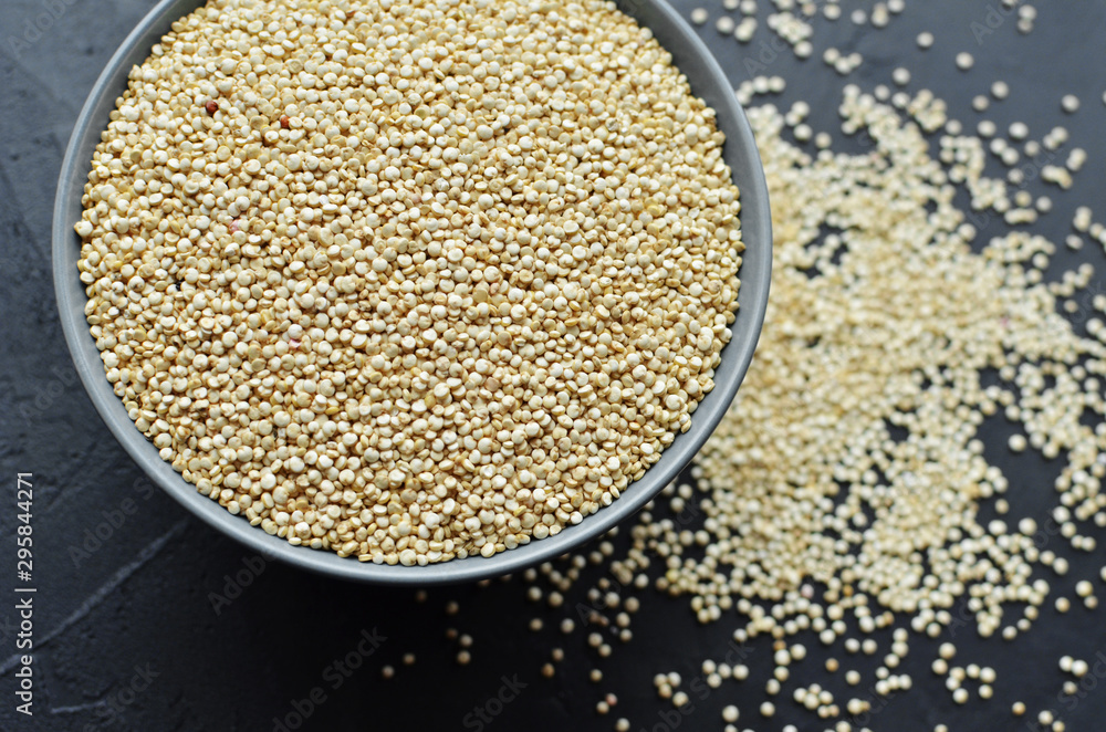 Dry organic quinoa seeds in ceramic bowl on dark grunge background Dry organic quinoa seeds in ceramic bowl on dark grunge background