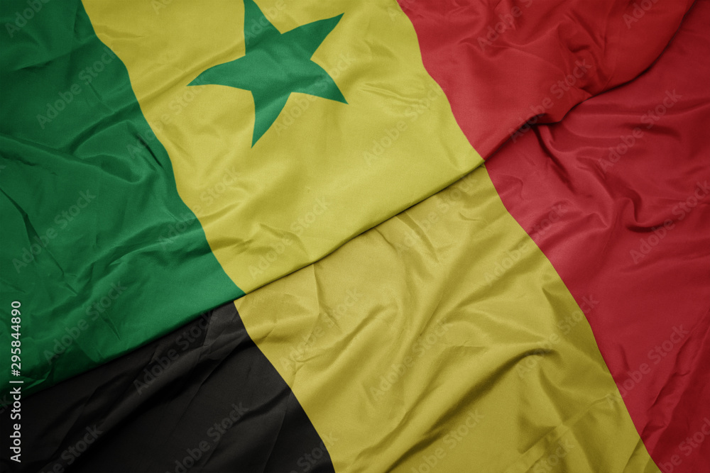 waving colorful flag of belgium and national flag of senegal.