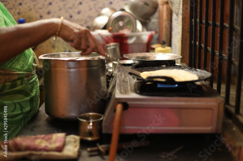 The woman standing next to stove and preparing dinner in the kitchen. Preparation of Indian food concept.
