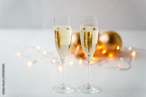 christmas, holidays and celebration concept - two glasses of champagne and decorations