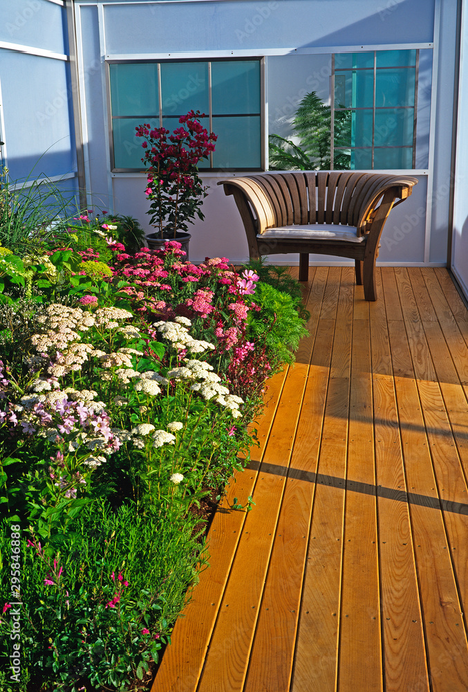 Achillea varities in an enclosed flower border with a seat and decking