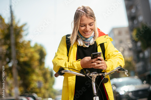 Beautiful woman with bicycle. Young woman using phone. 