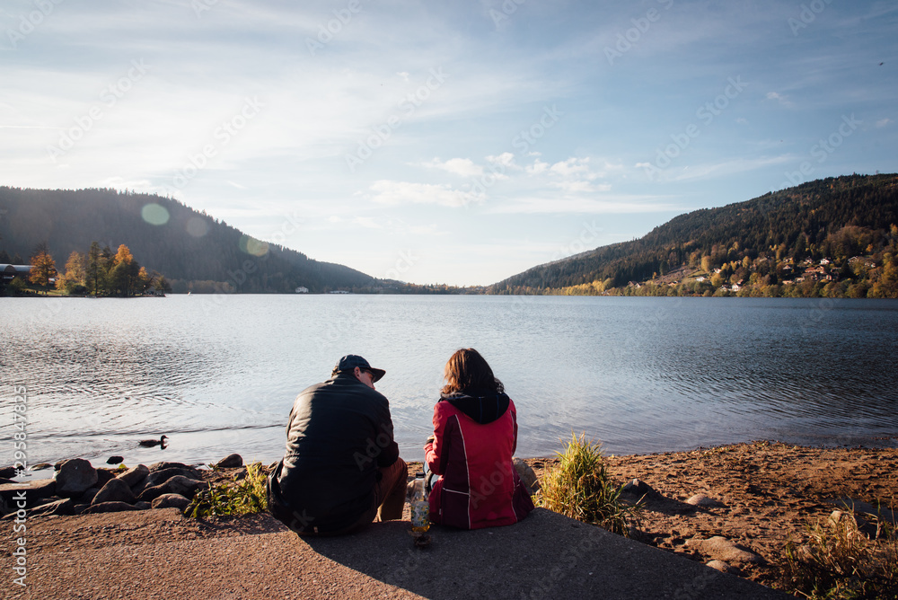 un couple d'amoureux devant le lac de Gérardmer. Des gens assis devant un lac. Des amoureux regardant un lac. Le lac de Gérardmer dans les Vosges.