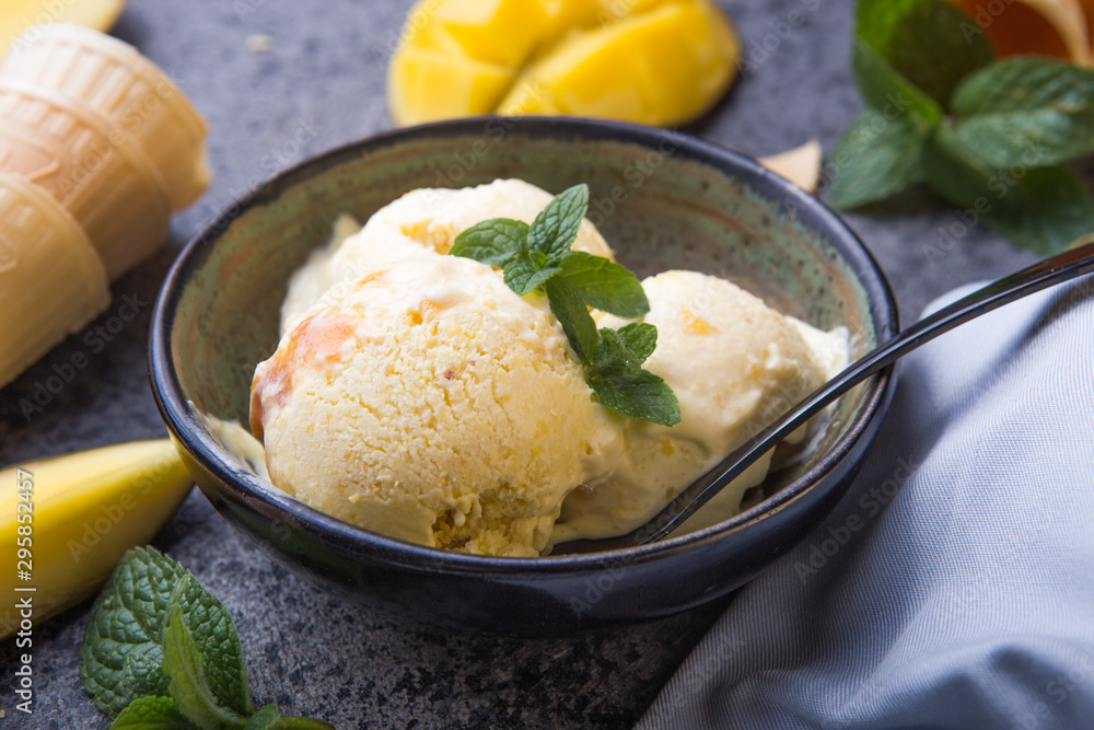 Close up bowl with vanilla ice cream covered with caramel sauce and fresh mango fruit on dark background. Selective focus. Summer dessert Close up bowl with vanilla ice cream covered with caramel sauce and fresh mango fruit on dark background. Selective focus. Summer dessert