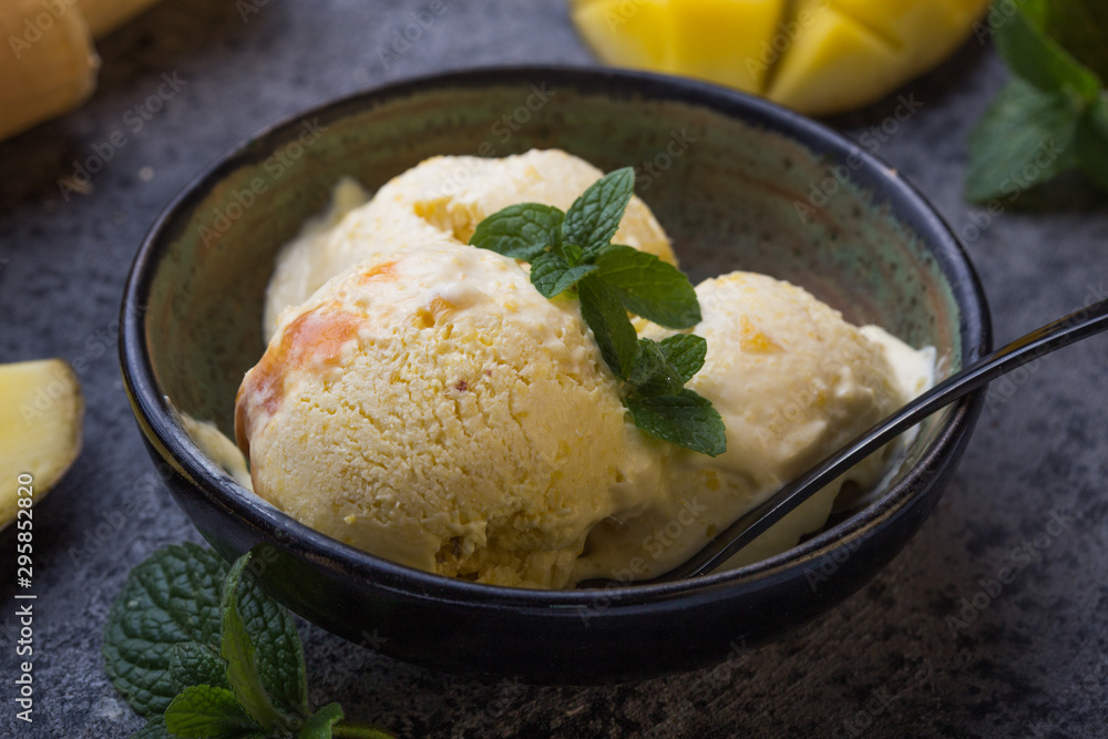 Close up bowl with vanilla ice cream covered with caramel sauce and fresh mango fruit on dark background. Selective focus. Summer dessert Close up bowl with vanilla ice cream covered with caramel sauce and fresh mango fruit on dark background. Selective focus. Summer dessert