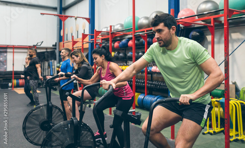 Group of athletes doing air bike at the gym photo