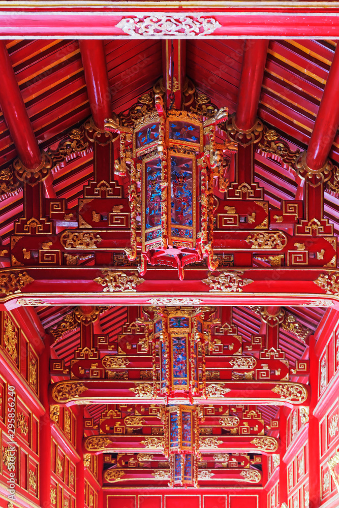 Amazing ornate ceiling in red colors in the corridor between buildings in Purple Forbidden city (Imperial Citadel) in Hue, Vietnam