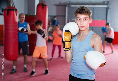 Teenage boy boxer in gloves posing during boxing