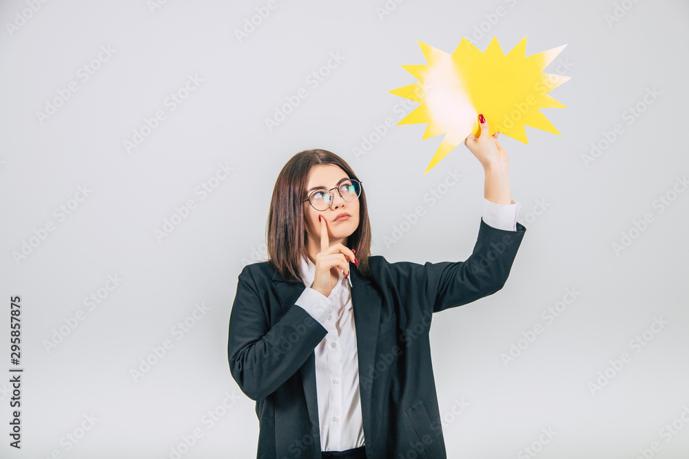Portrait of an excited young business woman raising up empty sparkle-like speech bubble, looking at it, thinking, keeping her finger on the cheek. Portrait of an excited young business woman raising up empty sparkle-like speech bubble, looking at it, thinking, keeping her finger on the cheek.