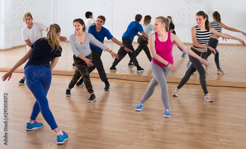 diligent teenage boys and girls learning in dance hall