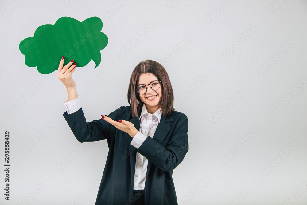 Lovely young businesslady standing with green cloud-like speech bubble, pointing her hand at it, smiling. Lovely young businesslady standing with green cloud-like speech bubble, pointing her hand at it, smiling.