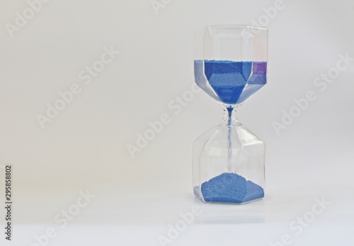 Old time measurement instrument with blue running sand. (hourglass)