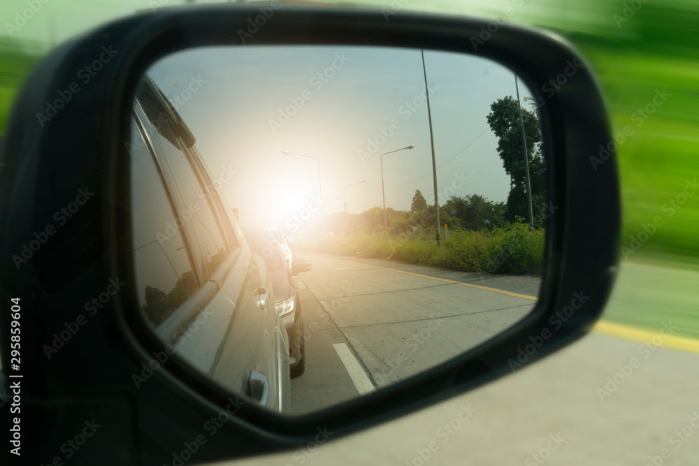 Close beside car form mirror view with other cars and sun light on the road.