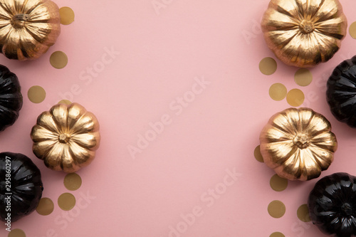 Gold and black pumpkins on pastel pink. Flat lay thanksgiving composition
