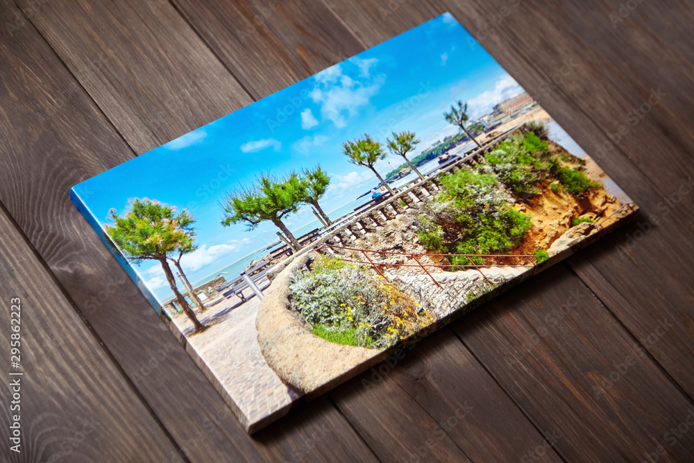 Canvas photo print on brown wooden background. Sample of gallery wrapping method. Colorful photography stretched on stretcher bar