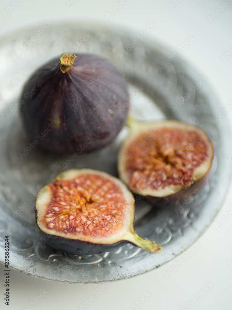 Two ripe figs. One whole fig and the second cut in half on a white table. Two ripe figs. One whole fig and the second cut in half on a white table.