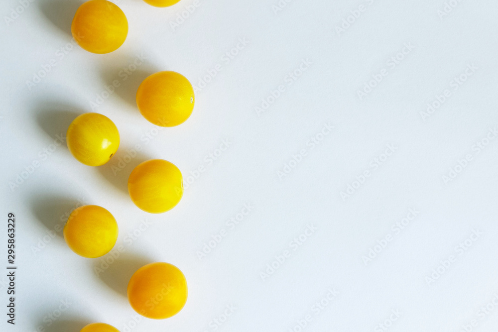 Fresh juicy yellow cherry tomatoes lie on a white background in a zigzag. Copy space