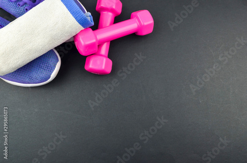 Fitness concept background with sneakers, dumbbells and towel. Top view with space for your text.