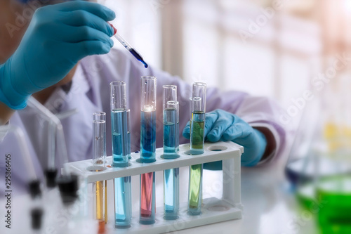 Laboratory concept; Scientist use dropper to transfer chemical reagent to test tube. He observe the chemical reaction in laboratory. photo