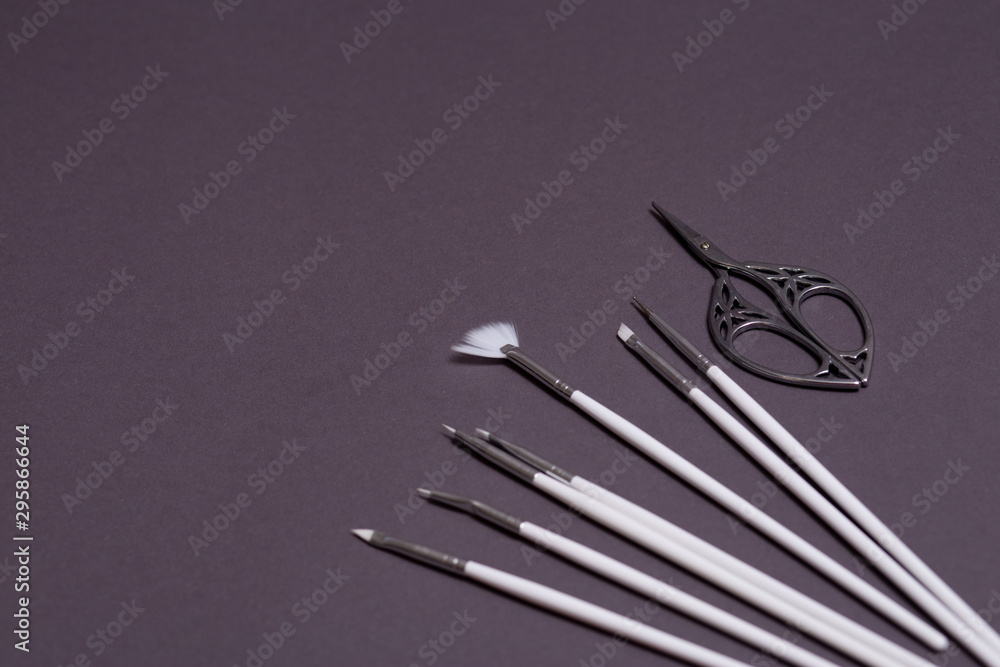 white brushes and beautiful openwork scissors for nail design on black background white brushes and beautiful openwork scissors for nail design on black background