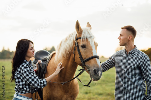 Portrait of happy loving couple spending time with horses on ranch