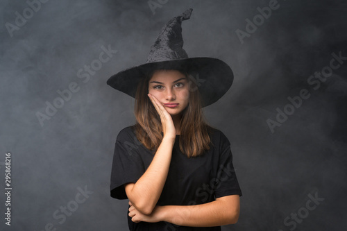 Girl with witch costume for halloween parties over isolated dark background unhappy and frustrated © luismolinero