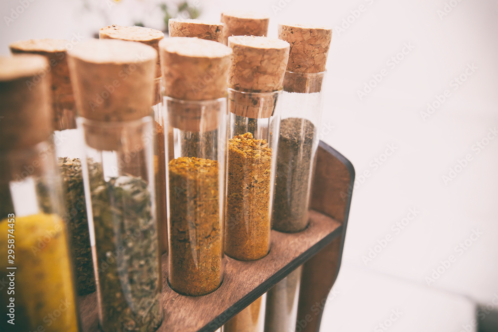 Glass flasks with different type of spices on the kitchen table - obrazy, fototapety, plakaty 