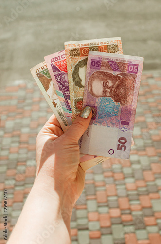 female hand holds a 500, 200, 100, 50 hryvnia bill against a street. Banknotes hryvnia is the official national currency of Ukraine. photo