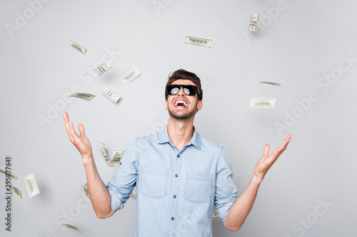 Photo of cheerful crazy excited funny freelancer having earned a lot of foreign currency smiling toothily isolated over grey color background poured with bucks photo