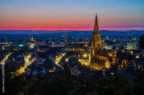 Germany  Intense colorful red afterglow sky decorating beautiful skyline of medieval city freiburg im breisgau with illuminated buildings and streets surrounding famous cathedral