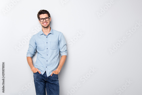Photo of cheerful funky positive intelligent man smiling toothily holding hands in pockets isolated over grey color background