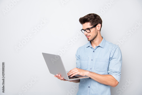 Photo of thoughtful focused clever interested freelancer holding laptop with hands wearing eyeglasses working on deadline project isolated grey color background