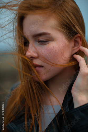 The wind plays with the bright red hair of a young girl.