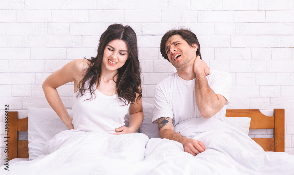 Fototapeta premium Young sad couple waking up, suffering from back and neck ache