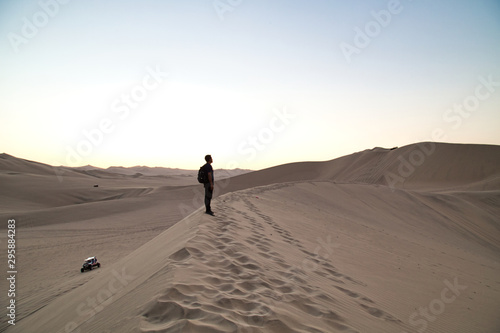 young man on sand in a desert near Huacachina  Ica region  Peru. The sunset desert view