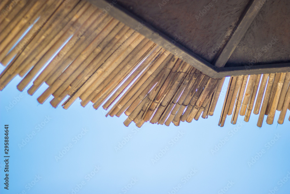 Wicker roof beach umbrella and blue sky. Natural bamboo sunshades and summer umbrella parasol on blue sea shore. Large straw beach umbrellas. Wicker roof beach umbrella and blue sky. Natural bamboo sunshades and summer umbrella parasol on blue sea shore. Large straw beach umbrellas.