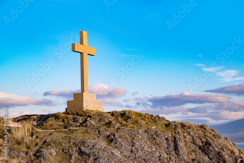 Stone cross on rocky mound in evening light